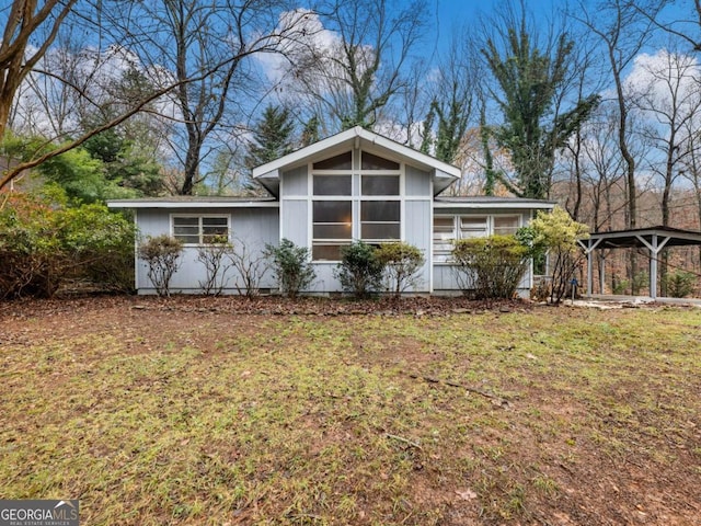 back of property with a lawn and a carport