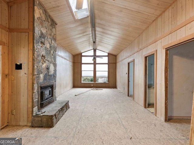 unfurnished living room featuring a wood stove, vaulted ceiling, wooden ceiling, and wood walls