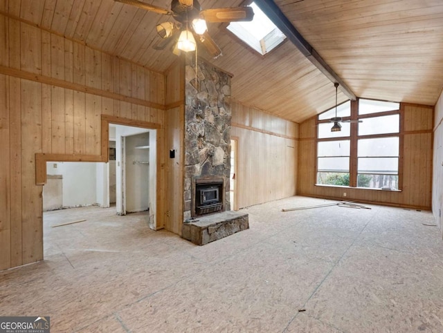 unfurnished living room with a skylight, ceiling fan, high vaulted ceiling, wooden ceiling, and a wood stove