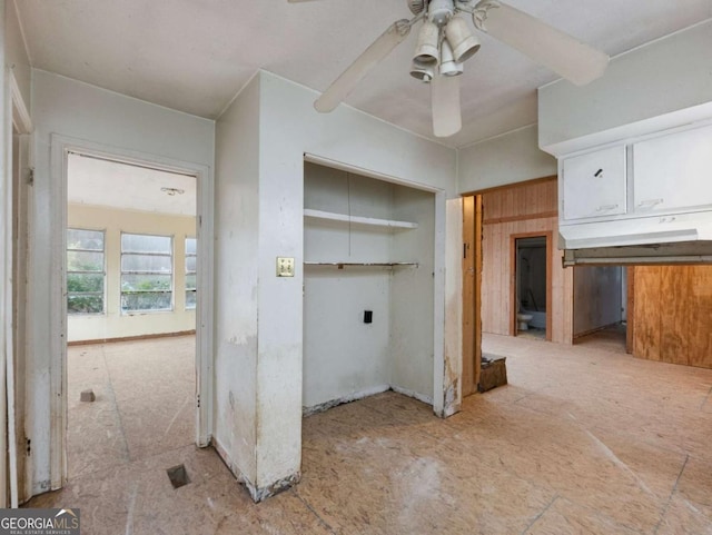 laundry area with ceiling fan and wooden walls