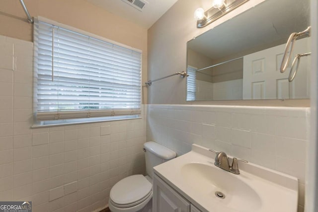 bathroom featuring vanity, tile walls, and toilet