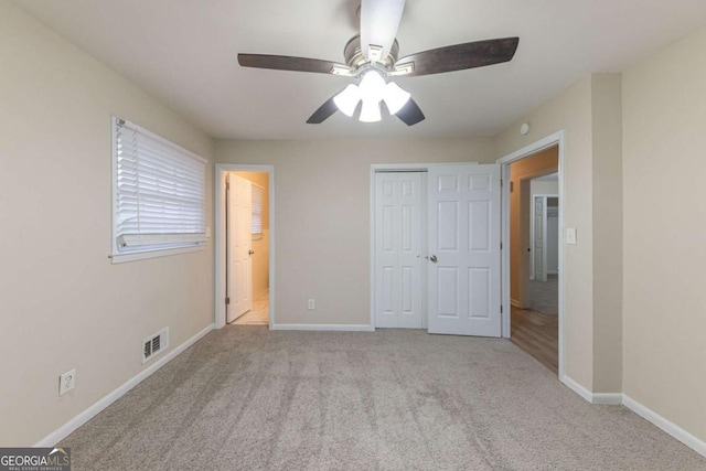 unfurnished bedroom featuring a closet, light colored carpet, and ceiling fan