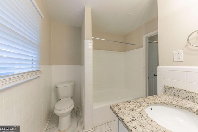 full bathroom featuring vanity, toilet, tile walls, and shower / washtub combination