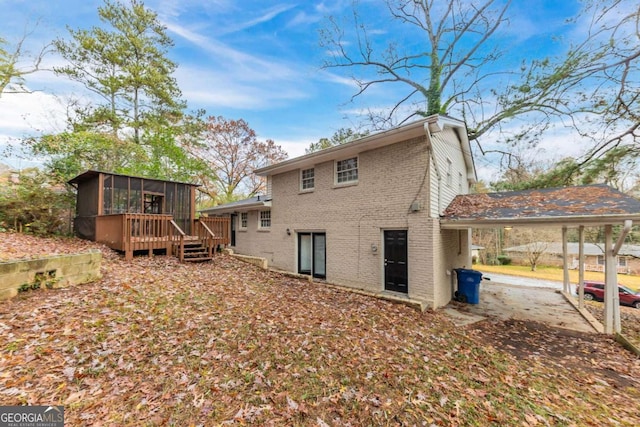 back of house with a sunroom, a carport, and a wooden deck