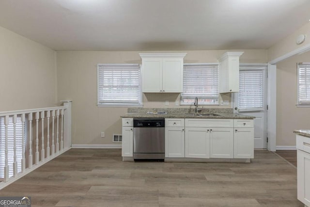 kitchen with dishwasher, sink, light stone counters, light hardwood / wood-style floors, and white cabinets