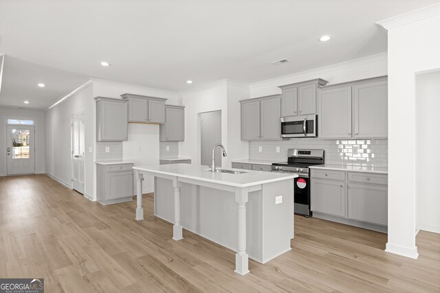 kitchen featuring hanging light fixtures, an island with sink, appliances with stainless steel finishes, tasteful backsplash, and a kitchen bar