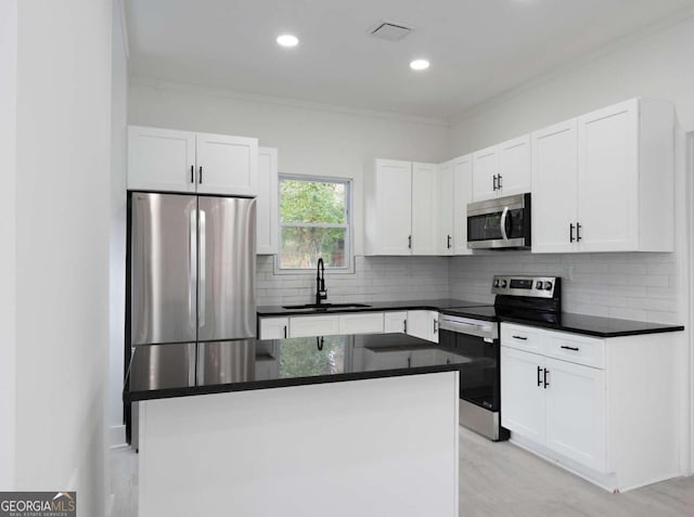 kitchen with sink, white cabinetry, stainless steel appliances, and ornamental molding