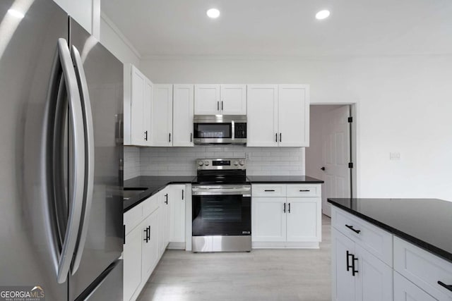 kitchen featuring decorative backsplash, white cabinetry, stainless steel appliances, and light hardwood / wood-style flooring