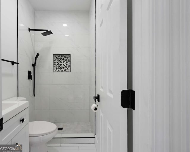 bathroom featuring a tile shower, vanity, and toilet