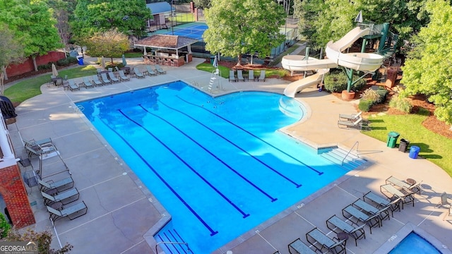 view of swimming pool featuring a water slide and a patio