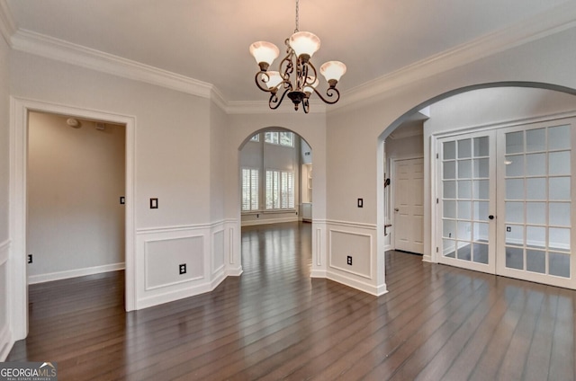 unfurnished dining area featuring crown molding, french doors, dark wood-type flooring, and a notable chandelier