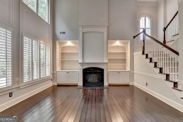 unfurnished living room featuring a fireplace, plenty of natural light, and dark wood-type flooring