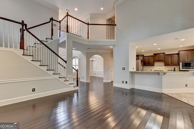 living room featuring a high ceiling, dark hardwood / wood-style flooring, an inviting chandelier, and crown molding