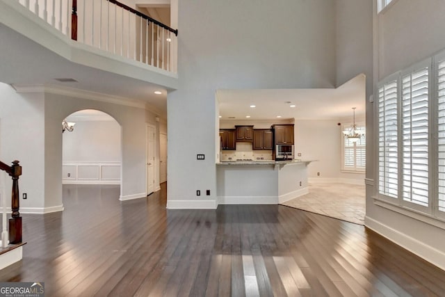 living room with crown molding, dark hardwood / wood-style flooring, a high ceiling, and a notable chandelier