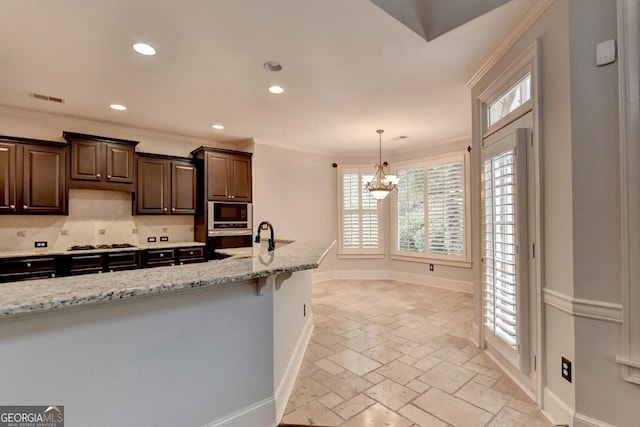 kitchen with ornamental molding, tasteful backsplash, a notable chandelier, dark brown cabinets, and stainless steel appliances