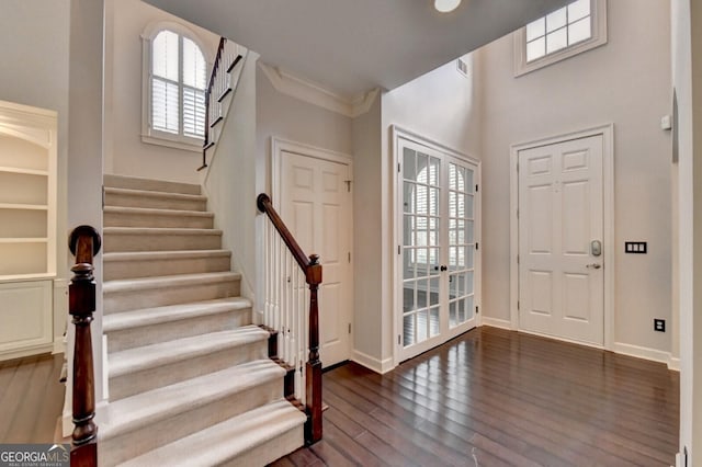 entryway with a healthy amount of sunlight, ornamental molding, dark wood-type flooring, and french doors