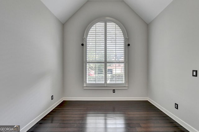 spare room featuring dark hardwood / wood-style floors, lofted ceiling, and a wealth of natural light