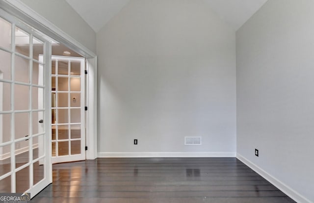 spare room featuring lofted ceiling, dark wood-type flooring, and french doors