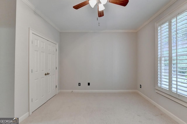 spare room with light carpet, crown molding, and ceiling fan