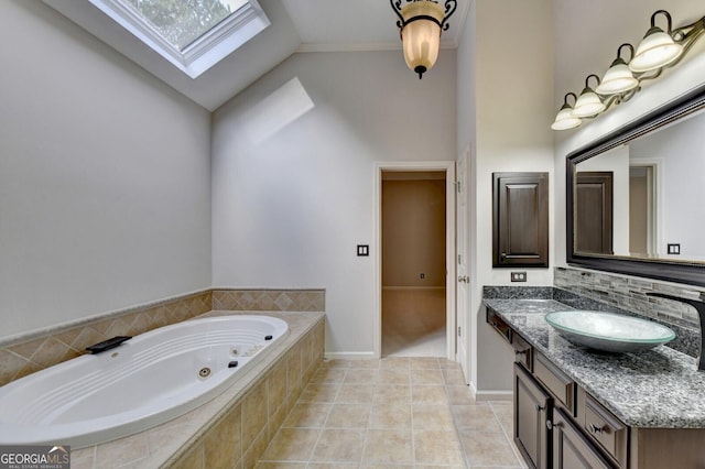 bathroom with ornamental molding, vaulted ceiling with skylight, vanity, tiled tub, and tile patterned flooring