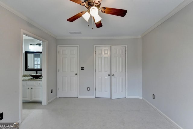 unfurnished bedroom with connected bathroom, light carpet, crown molding, and ceiling fan