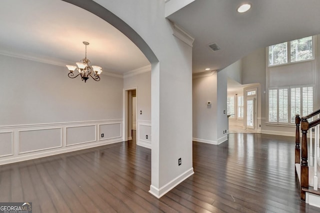 spare room with dark hardwood / wood-style flooring, ornamental molding, and a chandelier