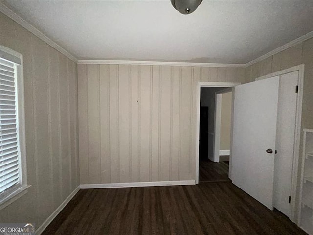 spare room featuring ornamental molding and dark wood-type flooring