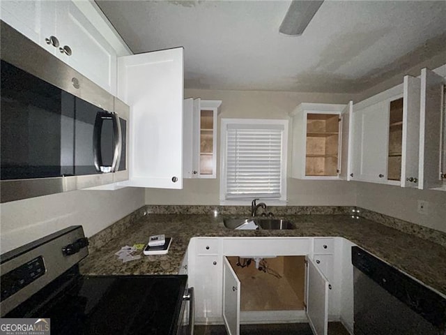 kitchen with appliances with stainless steel finishes, white cabinetry, dark stone counters, and sink