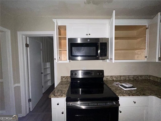 kitchen with black electric range oven, white cabinetry, and dark stone counters