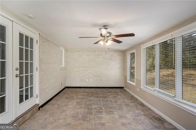 spare room featuring ceiling fan and brick wall