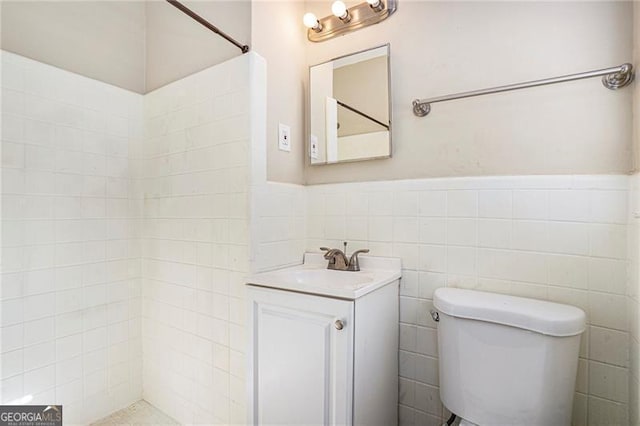 bathroom with vanity, toilet, and tile walls