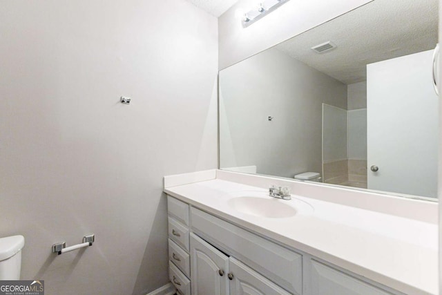 bathroom with vanity, toilet, and a textured ceiling