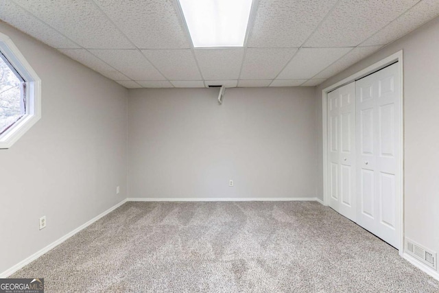 basement featuring a drop ceiling and carpet