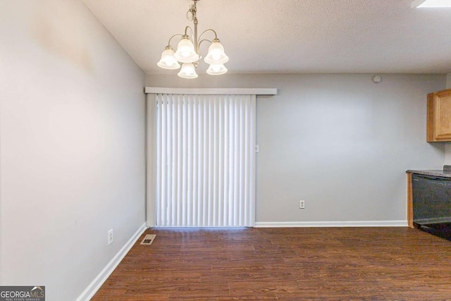 unfurnished dining area with dark hardwood / wood-style flooring, a textured ceiling, and a chandelier