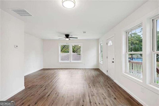 empty room with ceiling fan, dark wood-type flooring, and a wealth of natural light