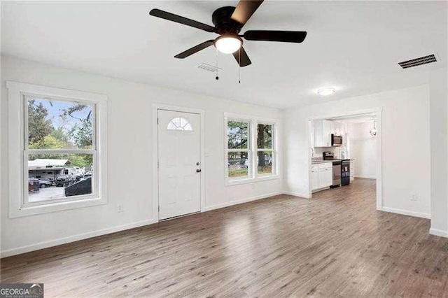 unfurnished living room with hardwood / wood-style flooring, a wealth of natural light, and ceiling fan