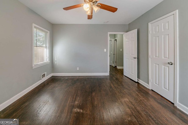 unfurnished bedroom with ceiling fan and dark wood-type flooring