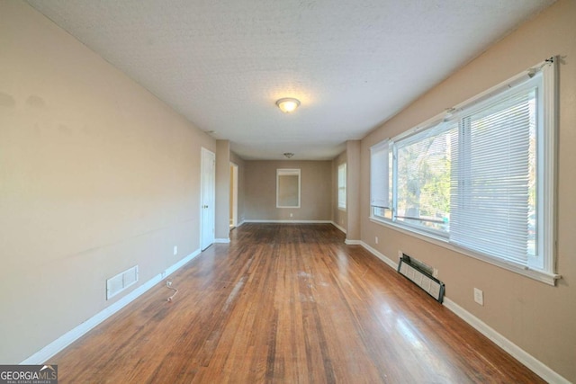 unfurnished room featuring radiator heating unit, a textured ceiling, and hardwood / wood-style flooring