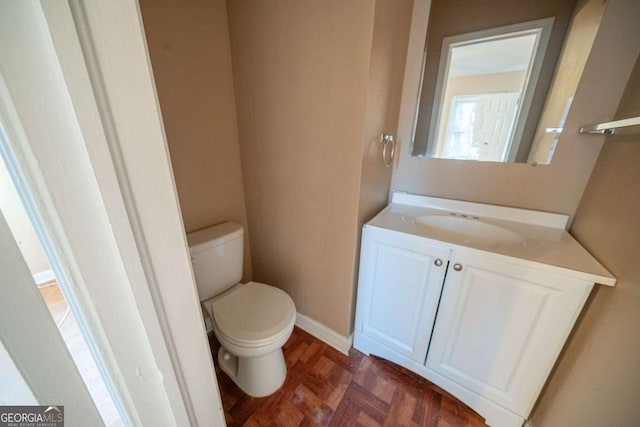 bathroom featuring parquet floors, vanity, and toilet