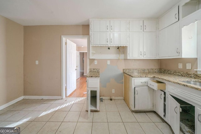 kitchen featuring white cabinets, light stone countertops, and light tile patterned floors