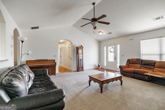 living room with a textured ceiling, light colored carpet, ceiling fan, and lofted ceiling