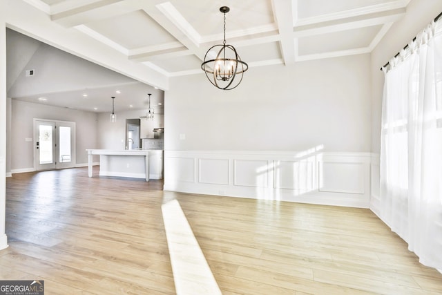 unfurnished dining area featuring light wood-type flooring, a notable chandelier, and coffered ceiling