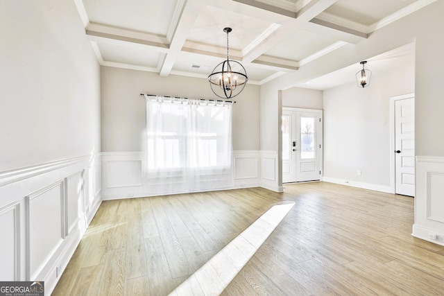 unfurnished living room with light wood-type flooring, coffered ceiling, ceiling fan with notable chandelier, beam ceiling, and a stone fireplace