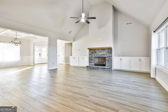 unfurnished living room featuring a stone fireplace, ceiling fan, high vaulted ceiling, and light hardwood / wood-style floors