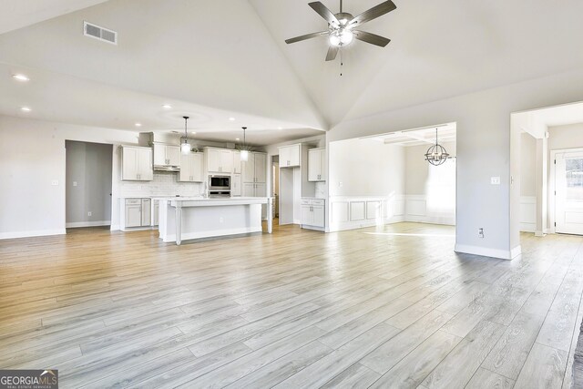 unfurnished living room featuring a fireplace, light hardwood / wood-style flooring, and high vaulted ceiling