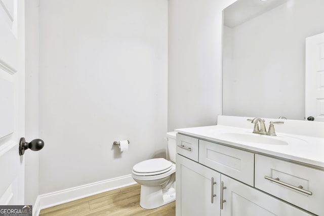 bathroom with hardwood / wood-style flooring, vanity, and toilet