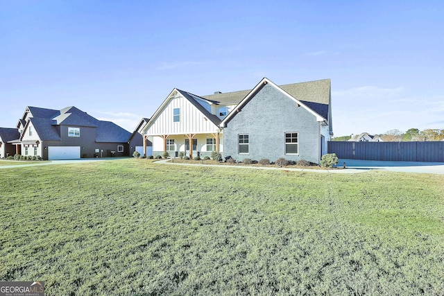 view of front of house with covered porch, brick siding, fence, board and batten siding, and a front yard