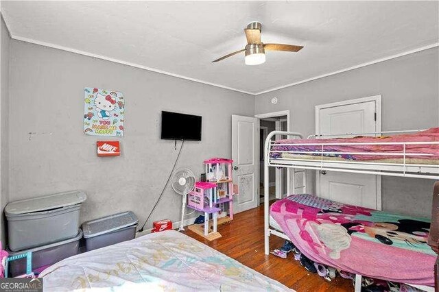 bedroom with ceiling fan, crown molding, and dark wood-type flooring