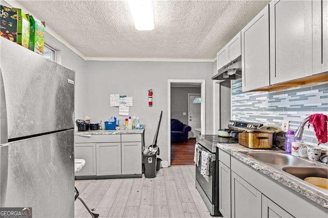 kitchen featuring sink, stainless steel appliances, light hardwood / wood-style floors, decorative backsplash, and ornamental molding