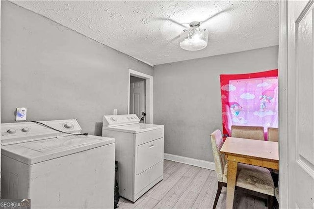 laundry area with light wood-type flooring, independent washer and dryer, and a textured ceiling